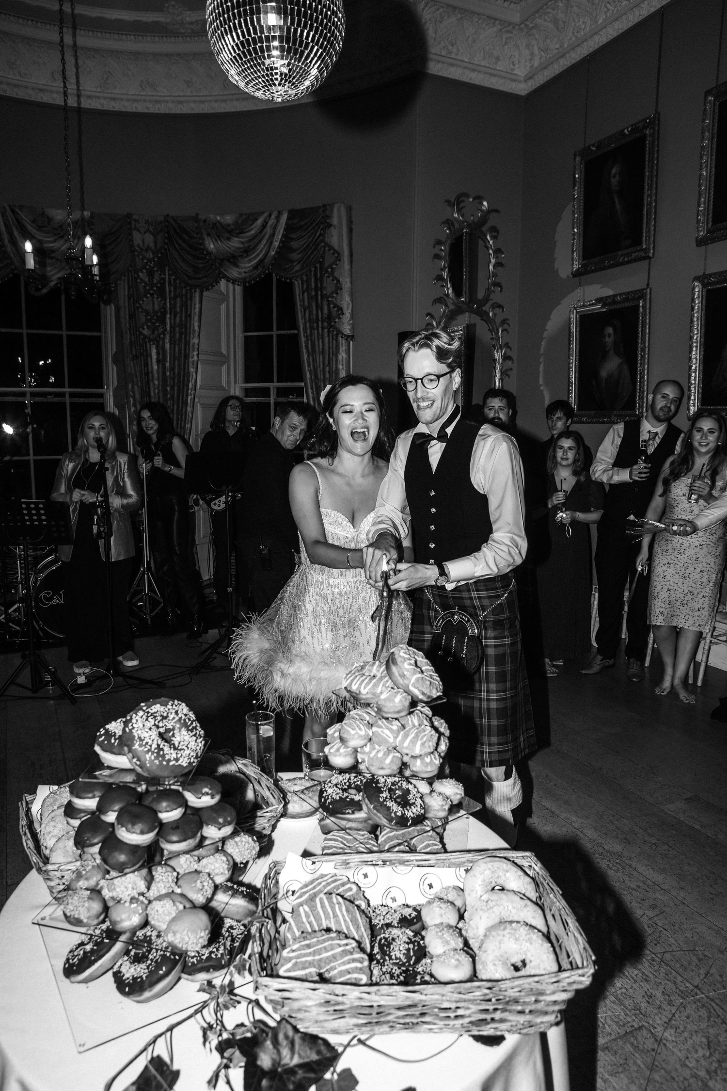 Couple standing by elegant dessert and appetizer table at wedding reception.