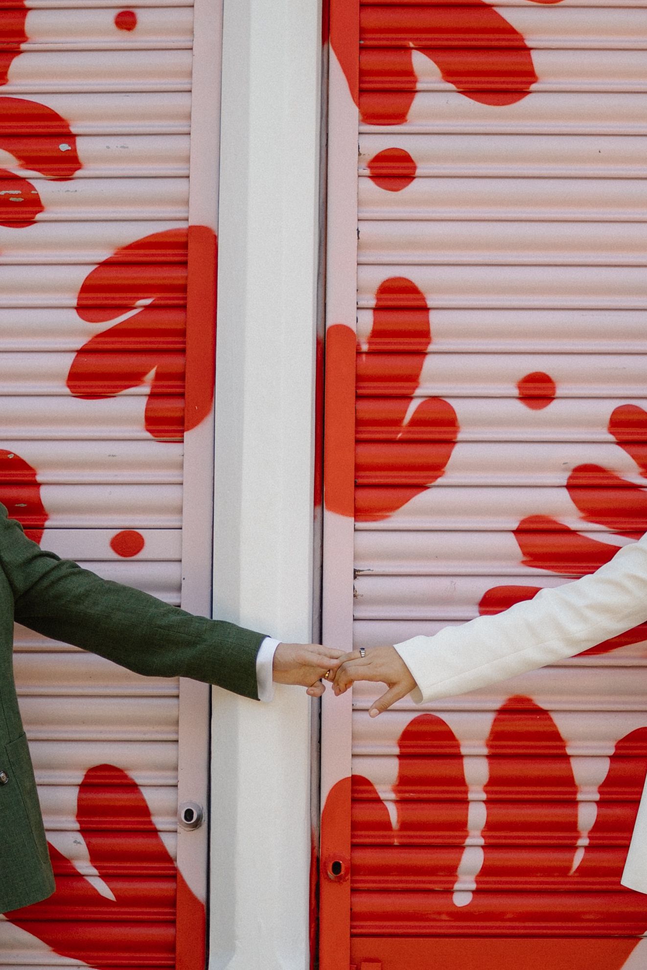 A couple strikes a playful pose against a backdrop of red floral designs.