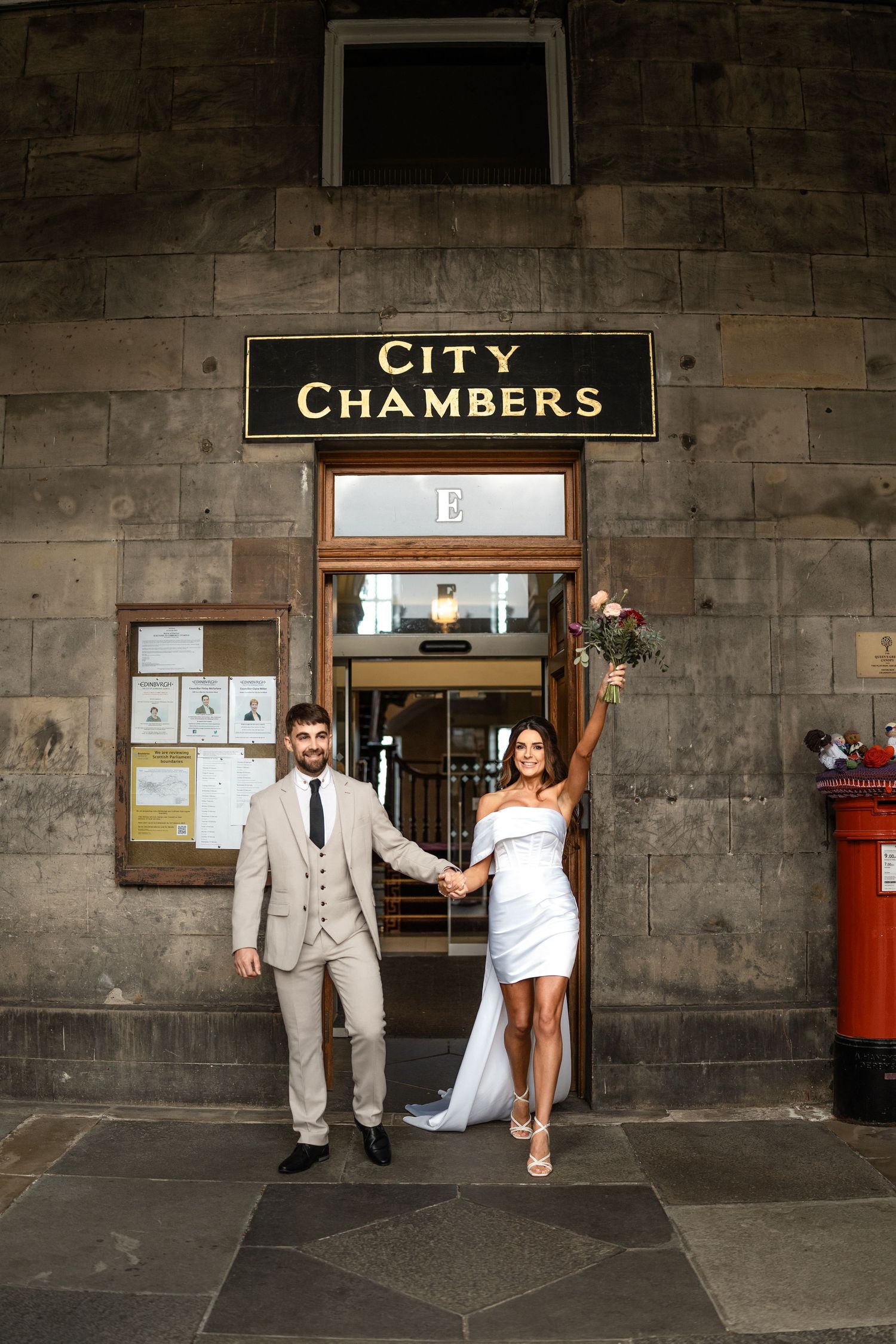 A couple poses outside City Chambers building entrance with vintage stone walls.
