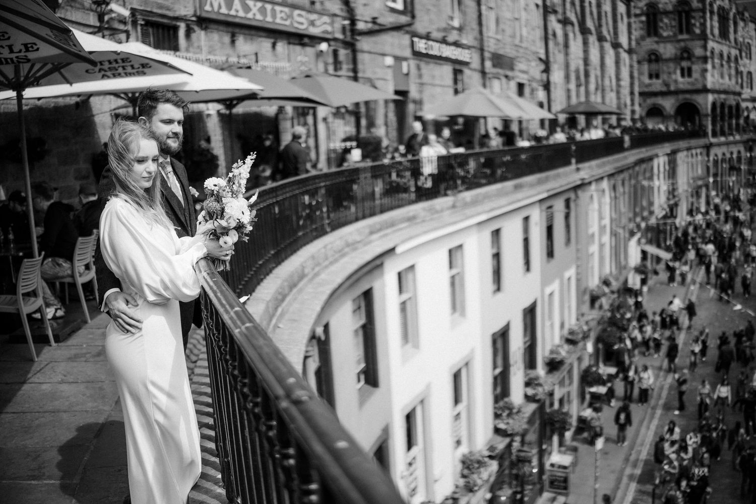 Bride and groom on balcony overlooking busy city street, black and white.