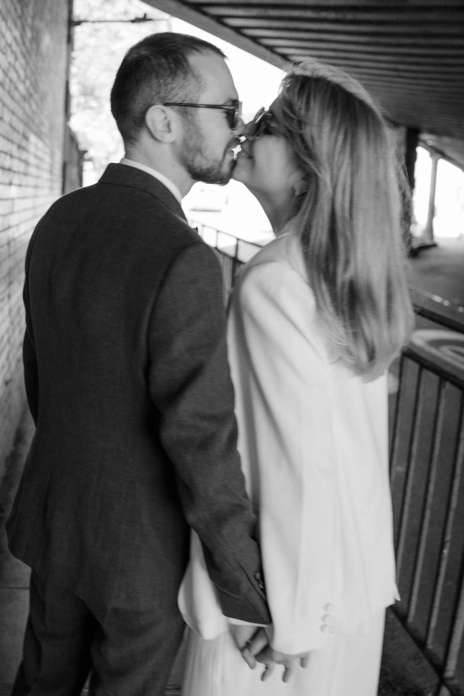 A couple in formal attire walking together in a dimly lit corridor.