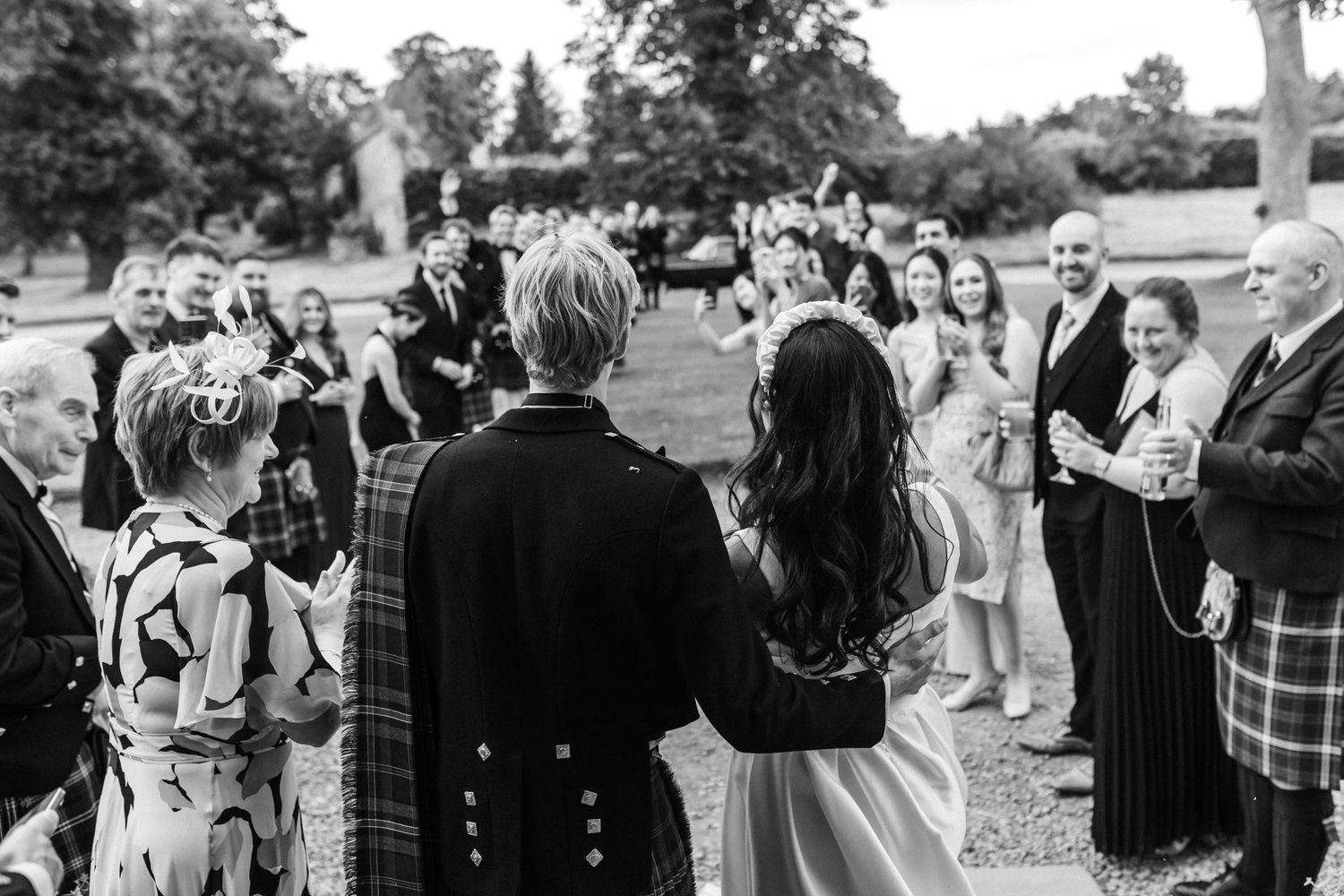 Black and white photo of wedding guests mingling at an outdoor reception.