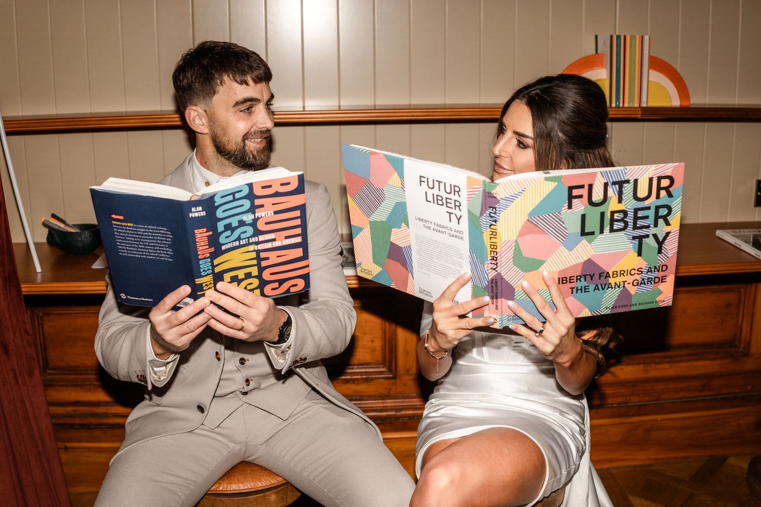 Couple reading children's books together in a casual indoor setting.