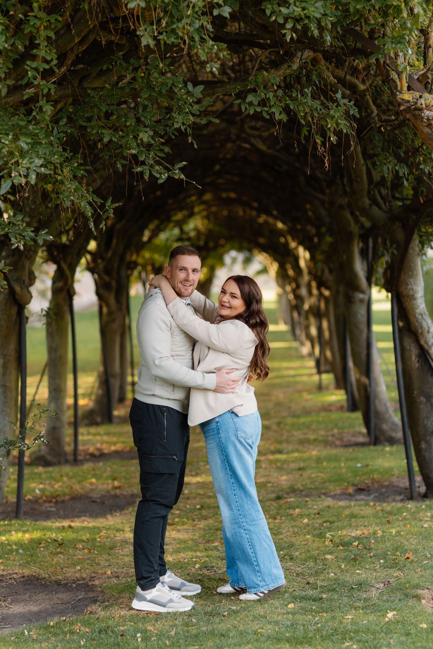 Tree-lined path provides romantic backdrop for couple's outdoor photography session.