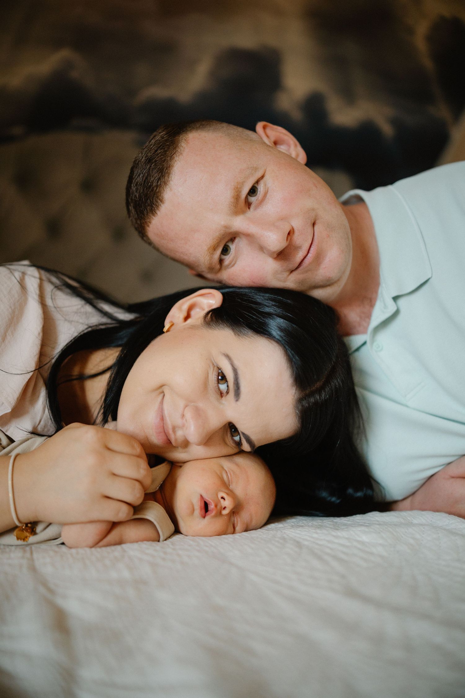 Couple sharing intimate moments while resting together on white bedding.