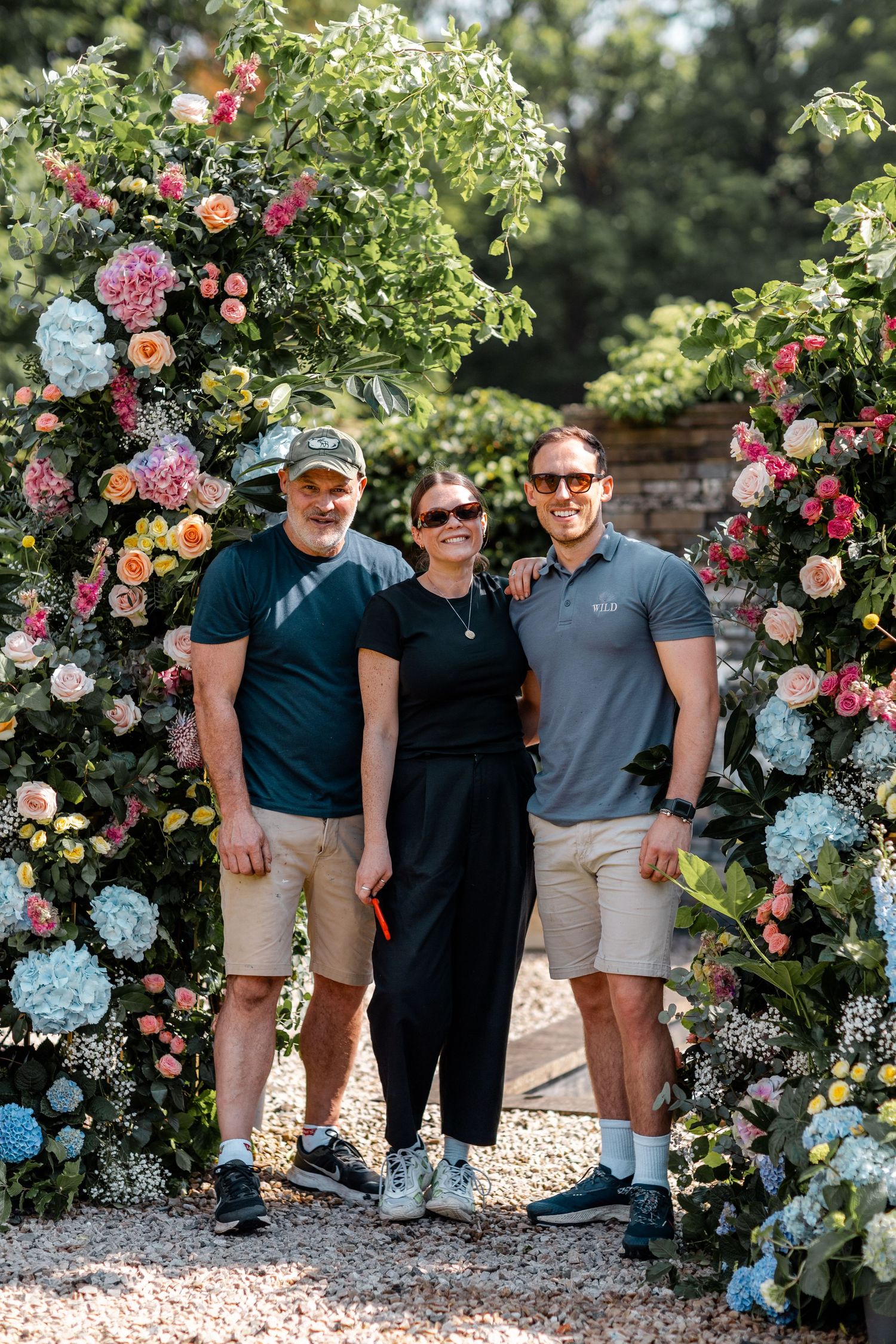 Team gathered in front of a beautiful rose garden with pink and blue blooms.