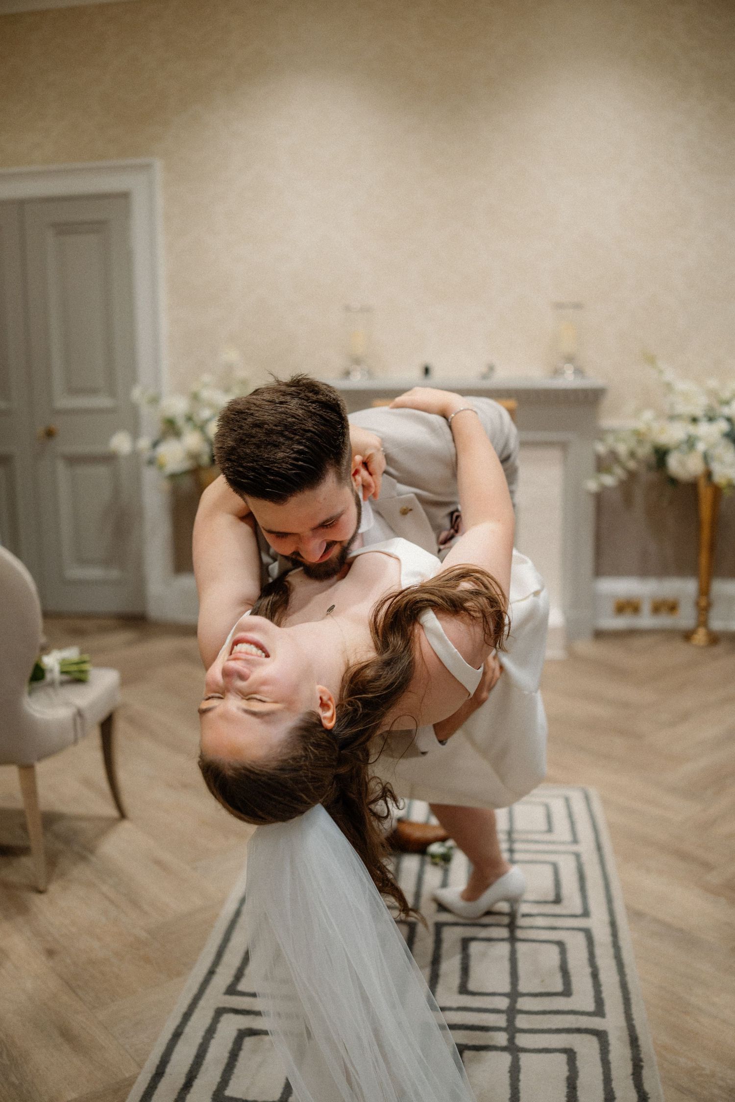 A romantic dance sequence showing a couple in formal attire dipping and twirling on a hardwood floor with white floral decor.