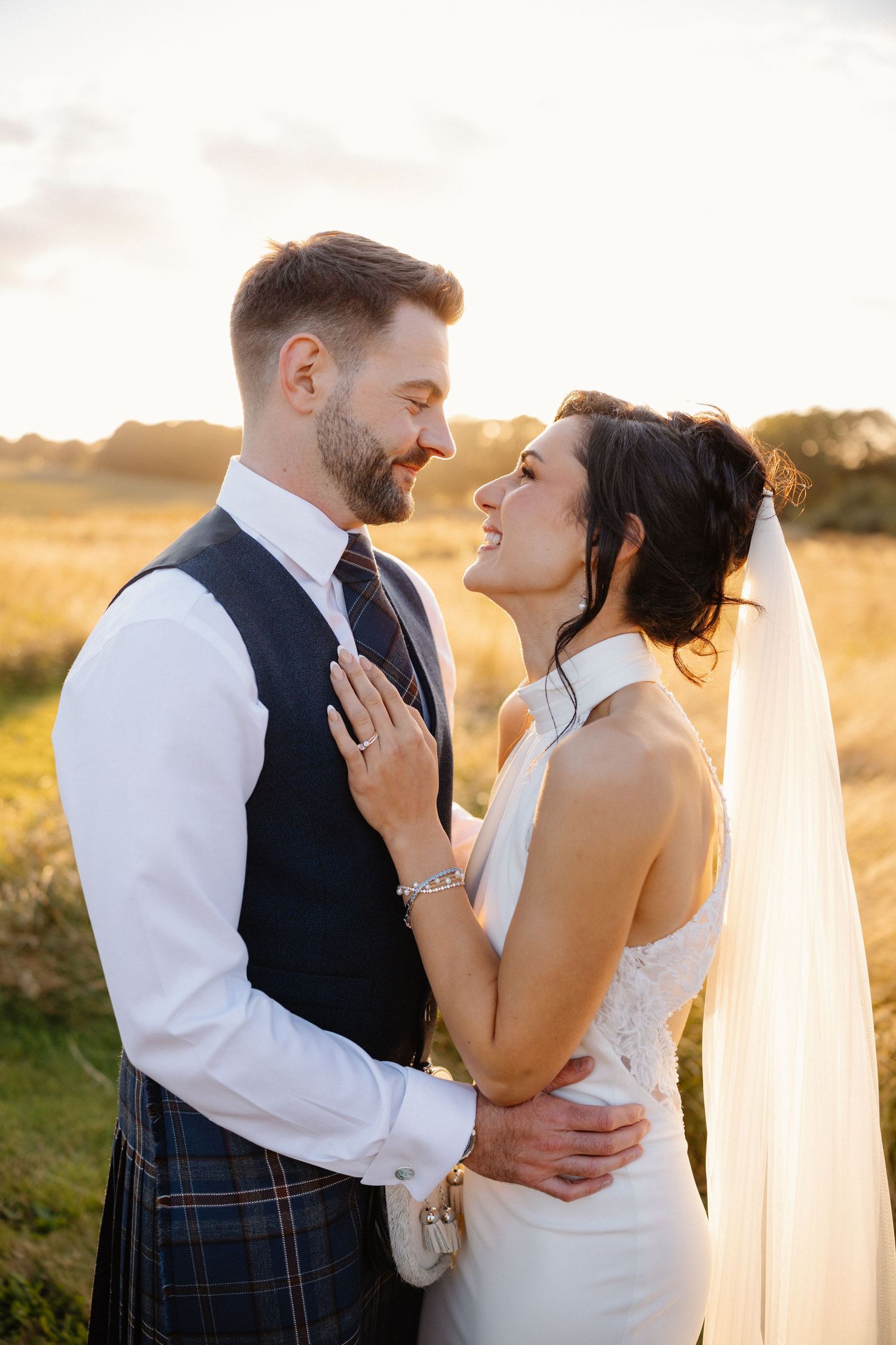 Romantic sunset wedding portraits with couple in traditional Scottish attire.