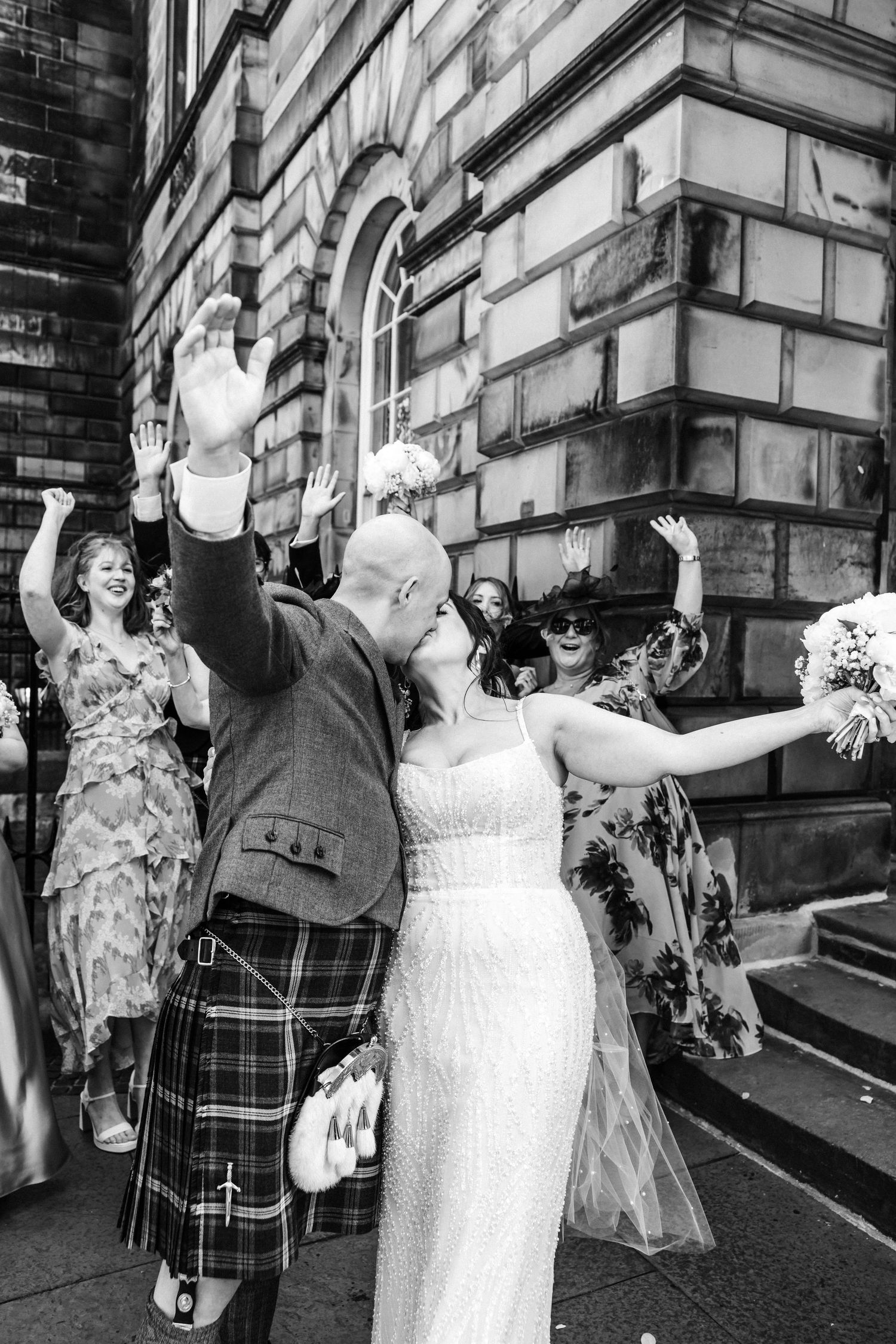 Kissing and hugging married couple outside City Chambers wedding in Edinburgh, Scotland, black and white