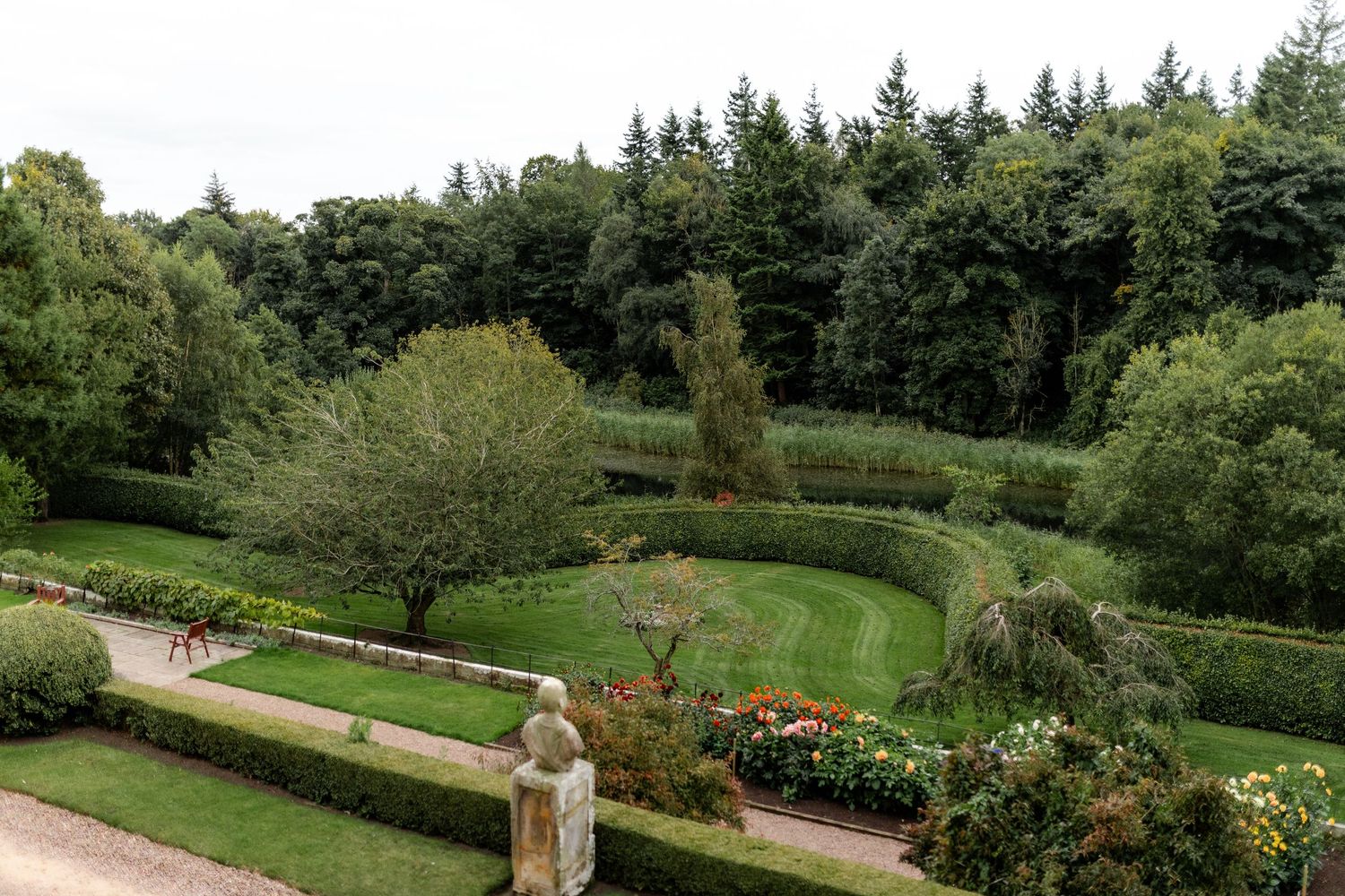 Manicured formal garden with hedges, pathways and colorful flowers at an estate property.