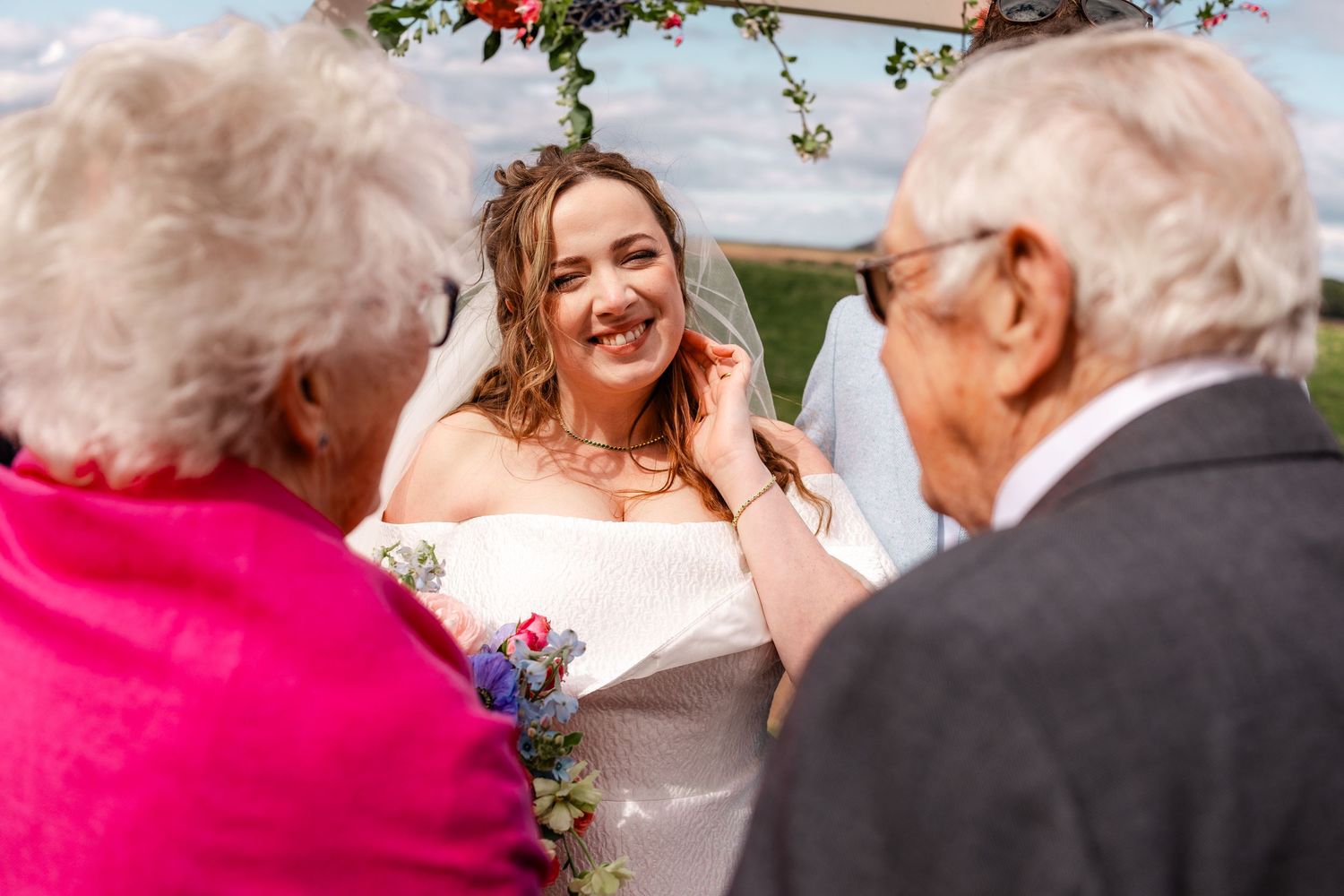 A floral arch frames a festive outdoor celebration with guests.