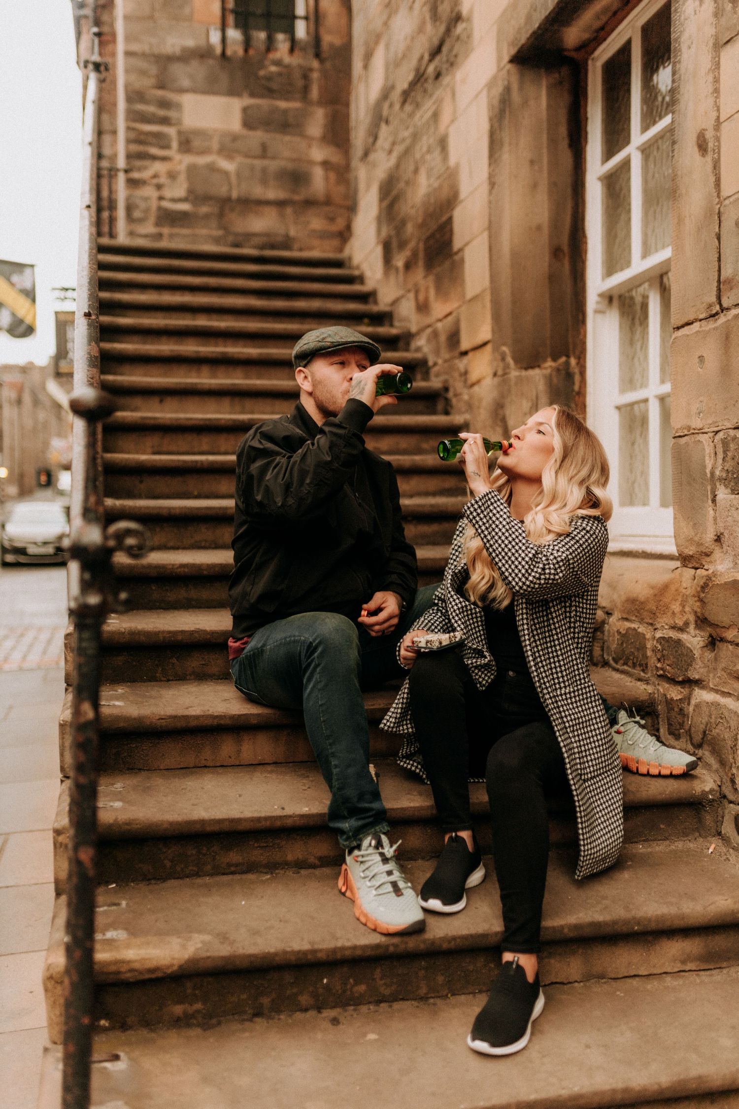 Playful couple sitting on stone steps sharing intimate moments in an urban setting.