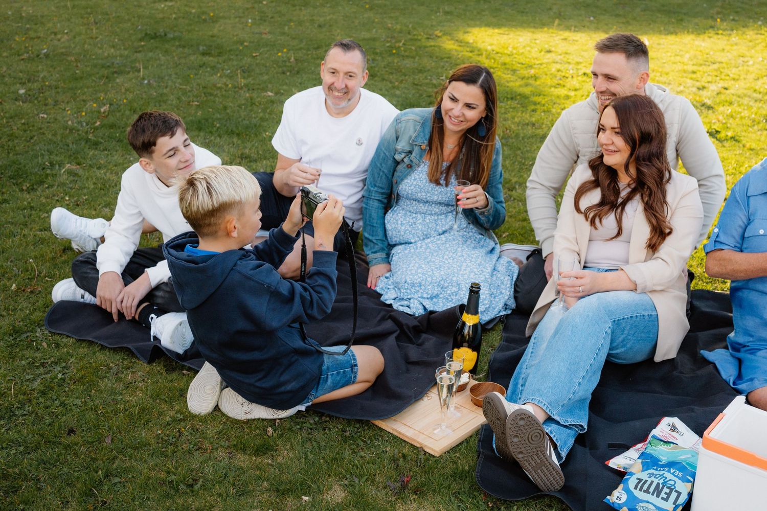 Group of friends relaxing together on a grassy lawn during a casual outdoor gathering.