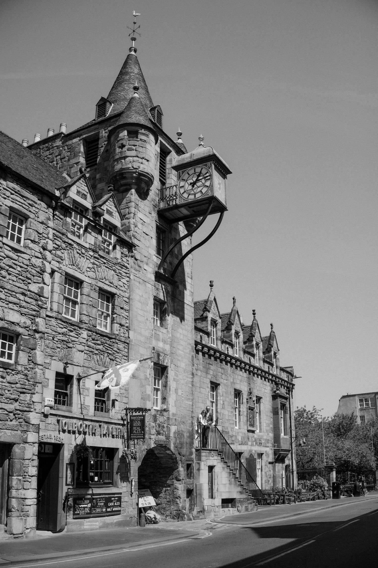 Black and white photo of historic stone building with turret and clock tower on Edinburgh Royal Mile.