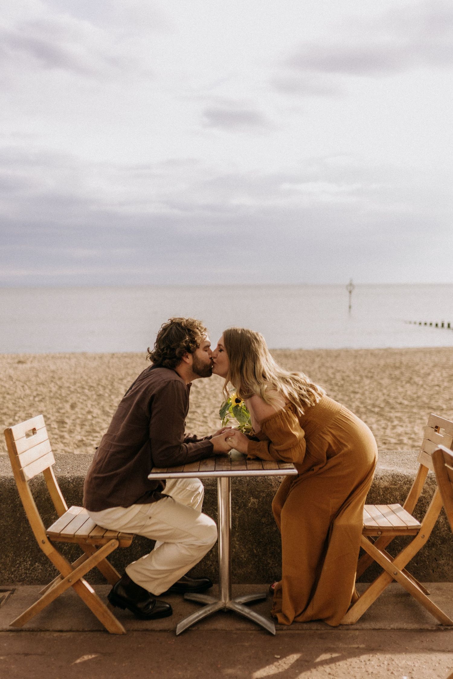 Couple sharing a romantic moment at a small table by the beach.
