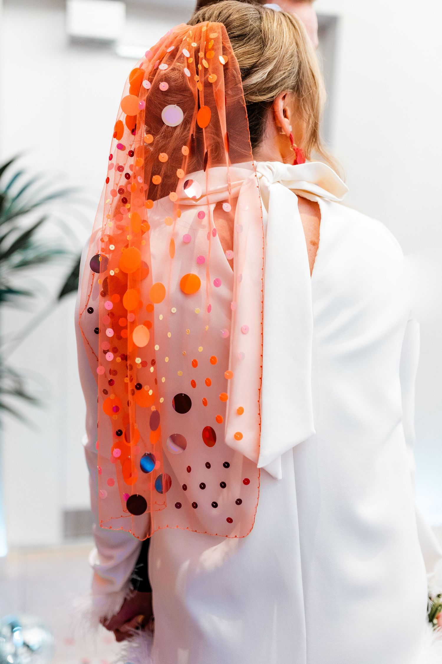 Close-up of a polka dot orange veil against a white outfit creating a vibrant color contrast.