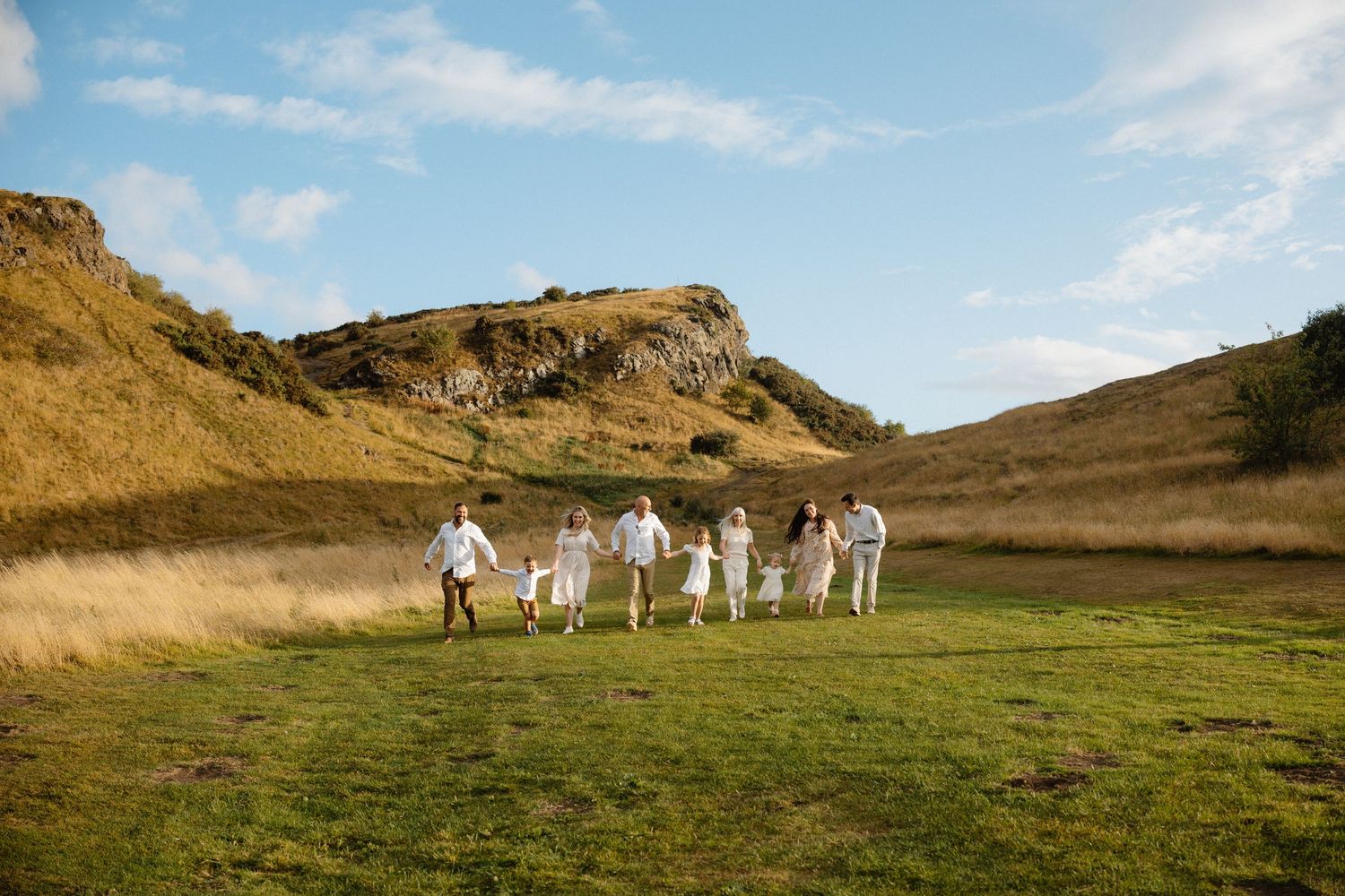 Group walks together across grassy hillside under blue sky.