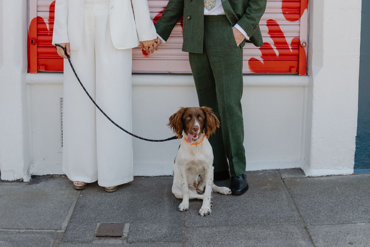 A white and red urban wall provides backdrop for a casual outdoor portrait with a dog.
