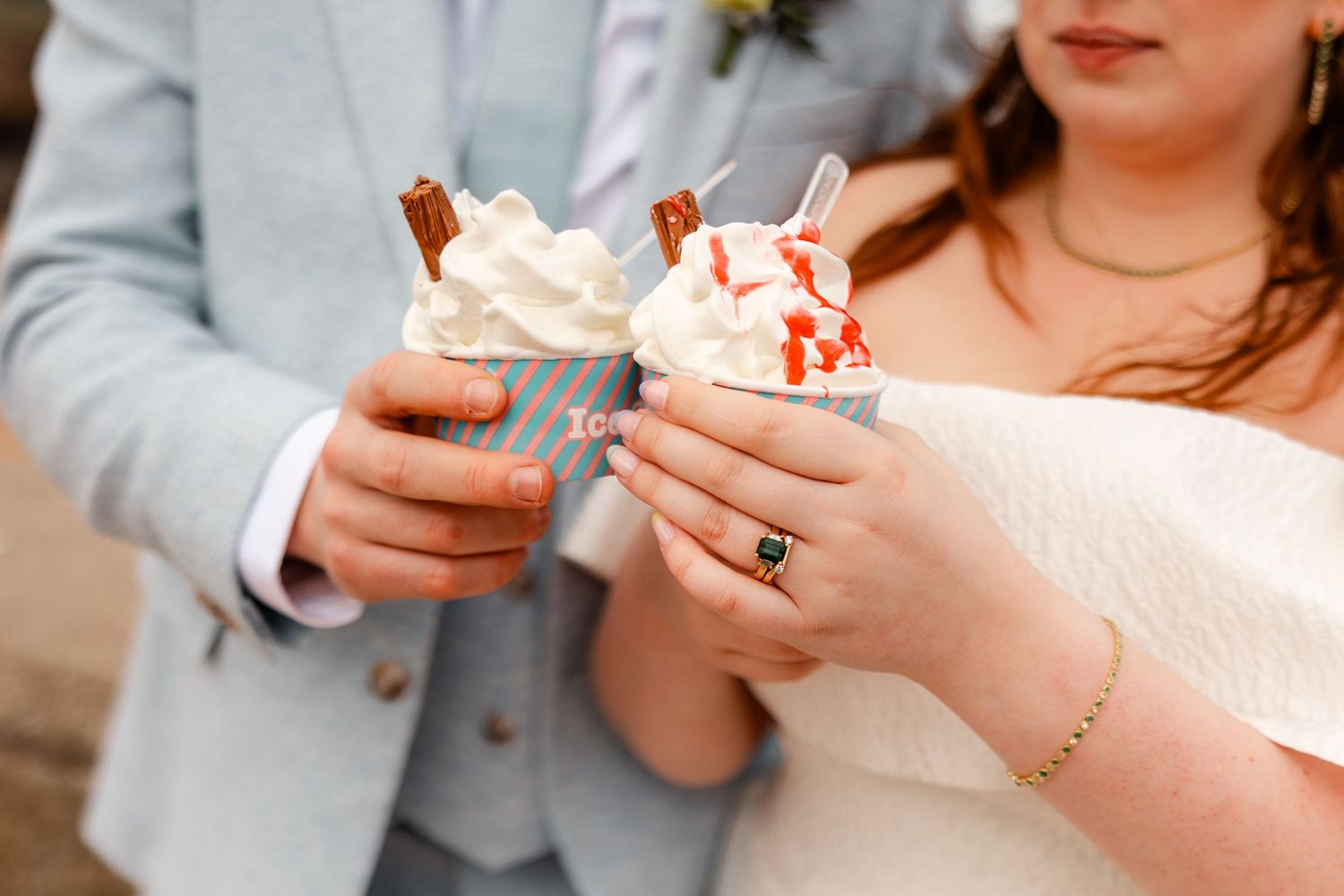 Bride and groom hold ice cream cones with chocolate flakes at their wedding celebration.