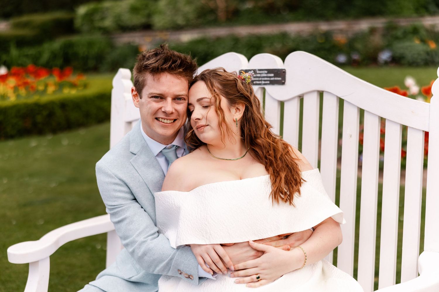 Romantic couple sharing intimate moment on white garden bench.