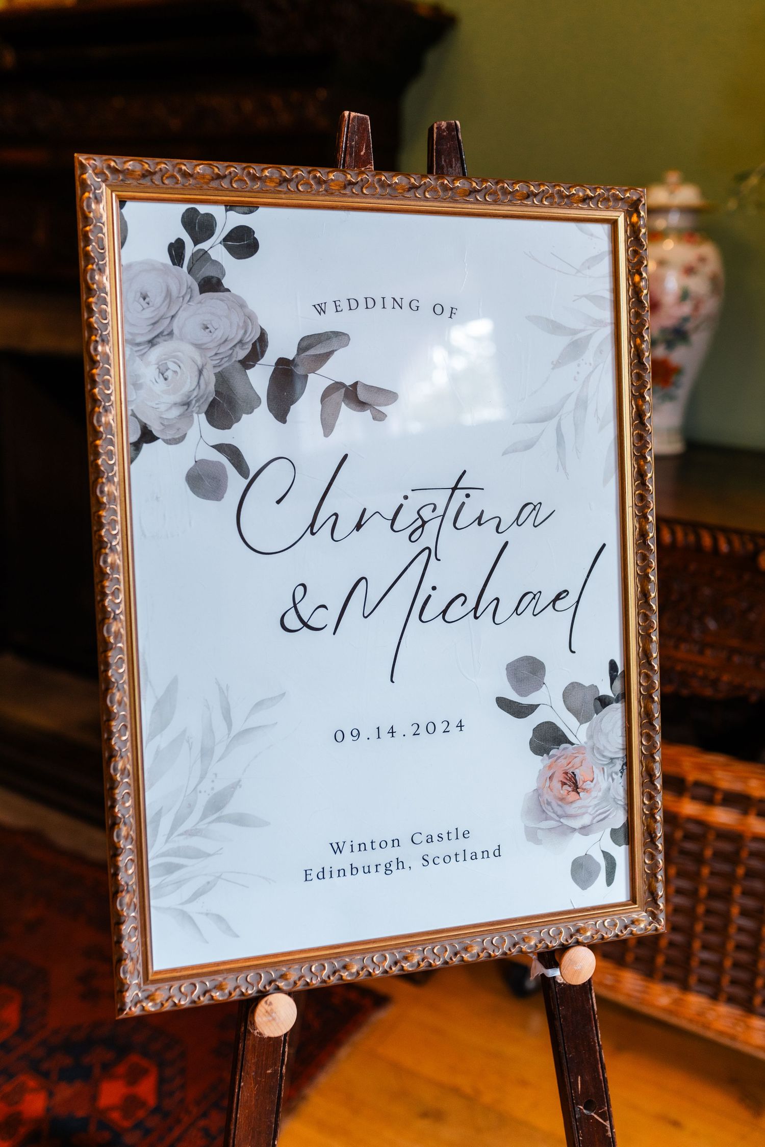 Elegant wedding signage with floral design displays couple's names and venue details.