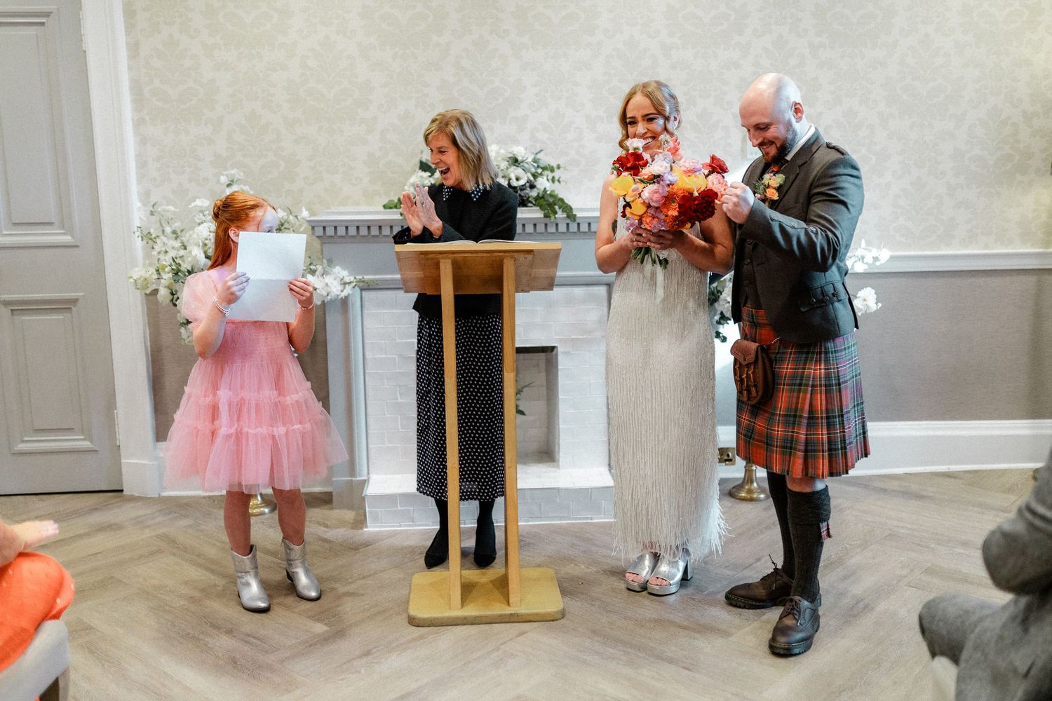Young children in formal attire play and interact during a wedding celebration.
