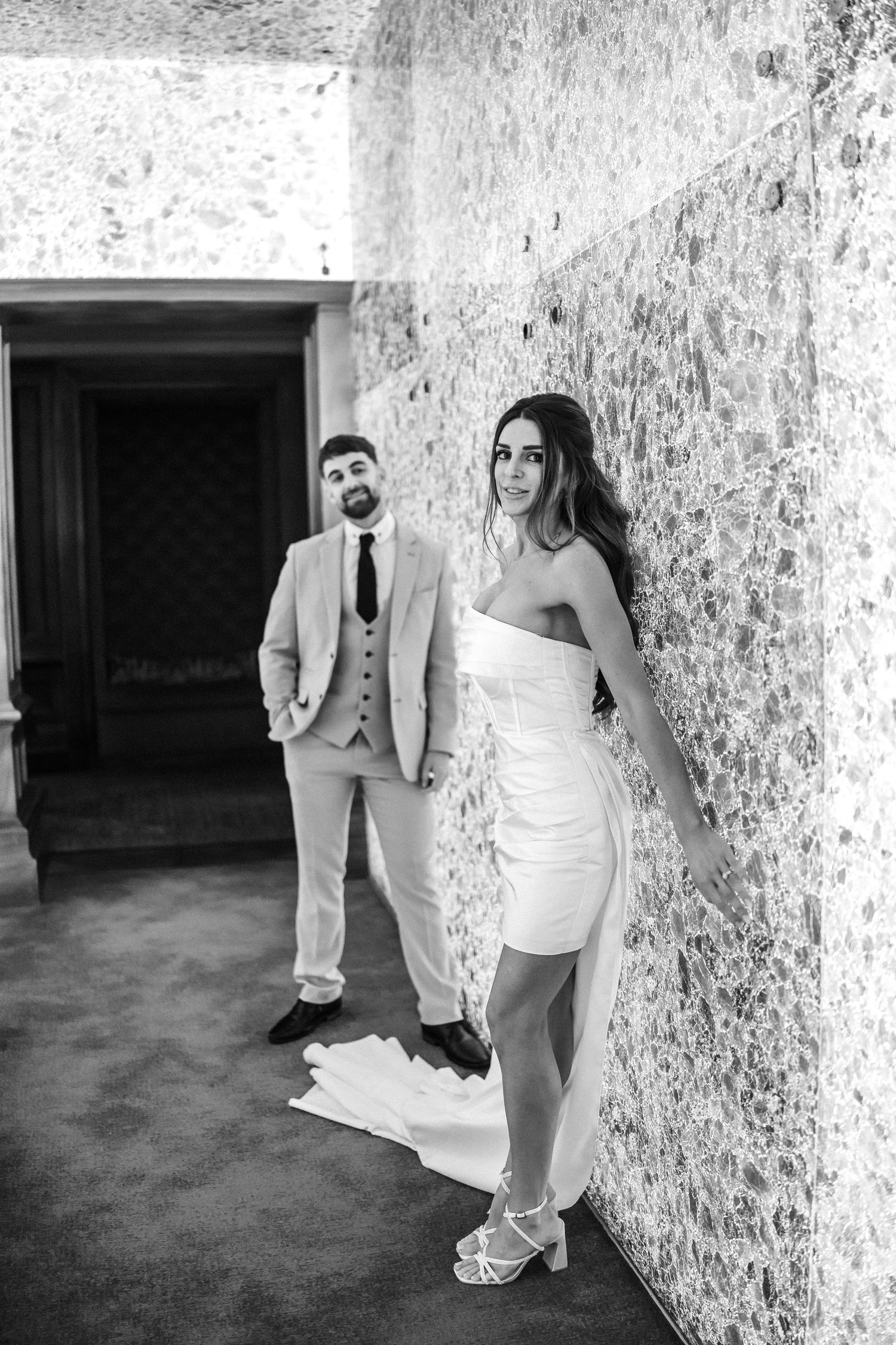 Black and white wedding photos against a textured wall show elegant poses.