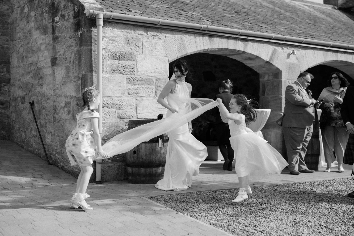 Wedding bride with kids playing courtyard at Rosebery Steading, Temple, Gorebridge, Scotland.