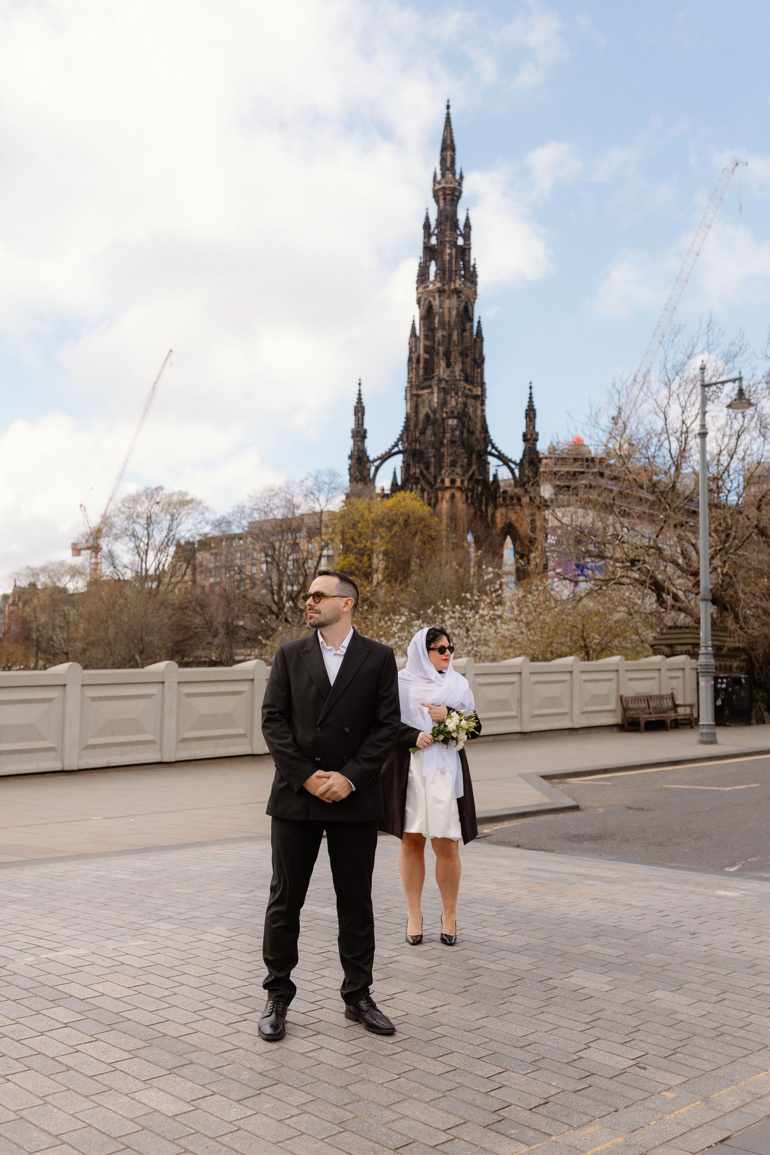 Bride and groom posing near the Scott Monument in Edinburgh on their wedding day.