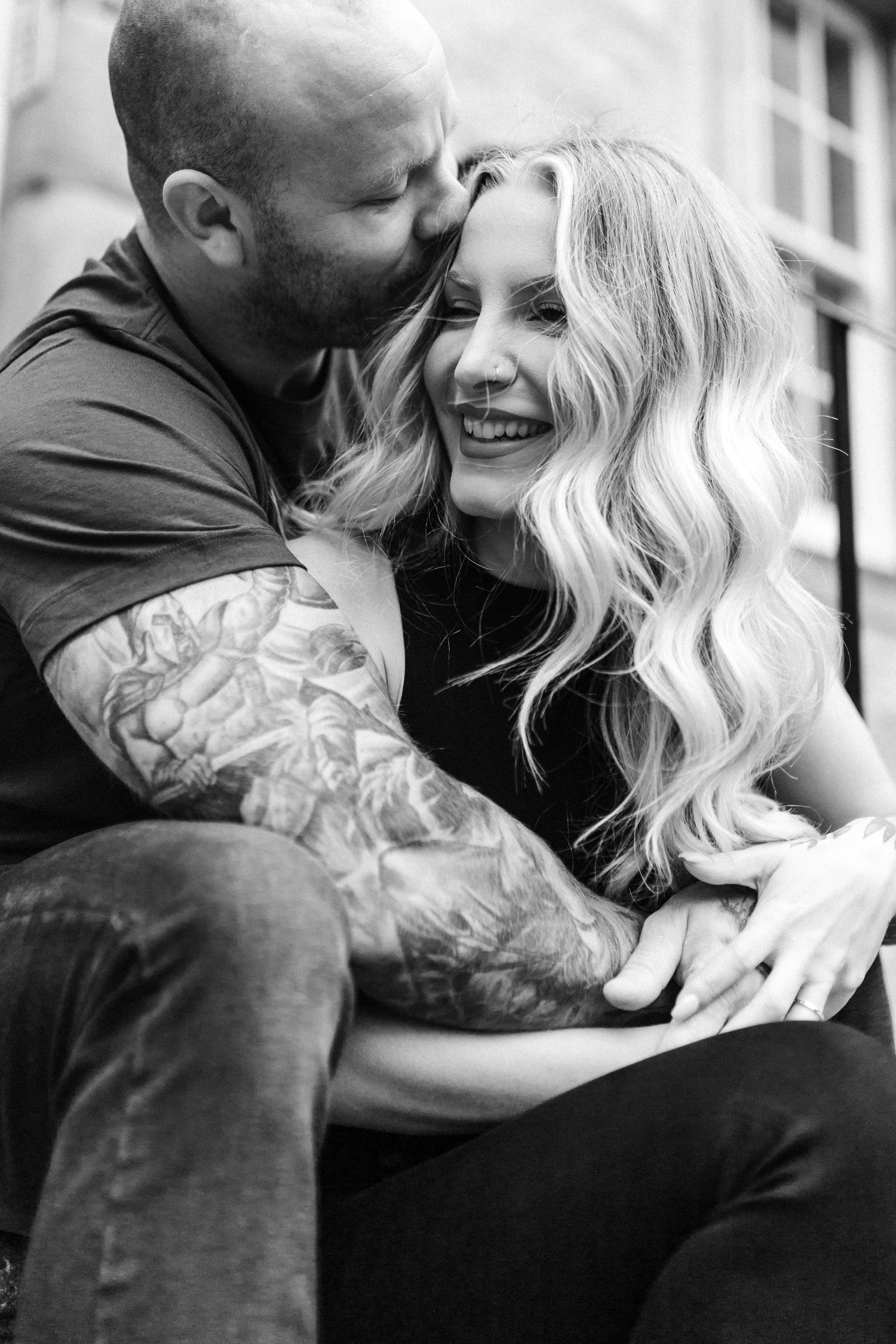 Black and white intimate portraits of couple embracing with visible tattoos.