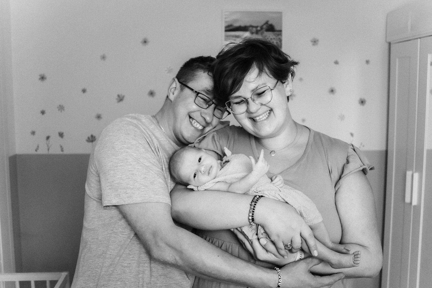 Tender family moment captured in black and white by a nursery crib.