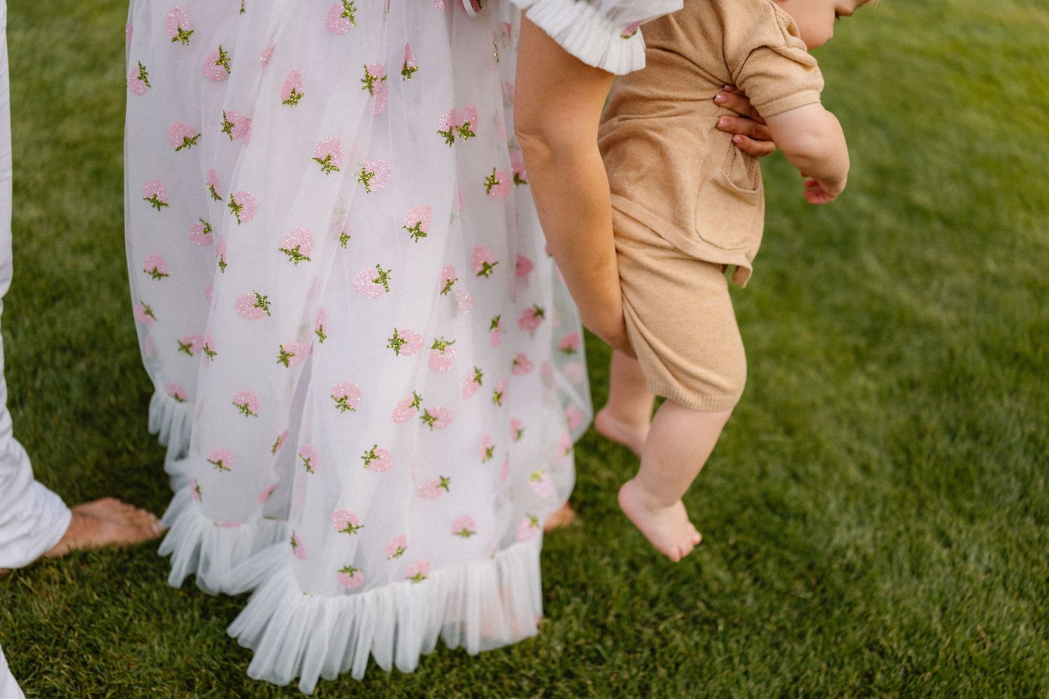 Romantic couple's portrait session on grass with floral dress and casual attire.