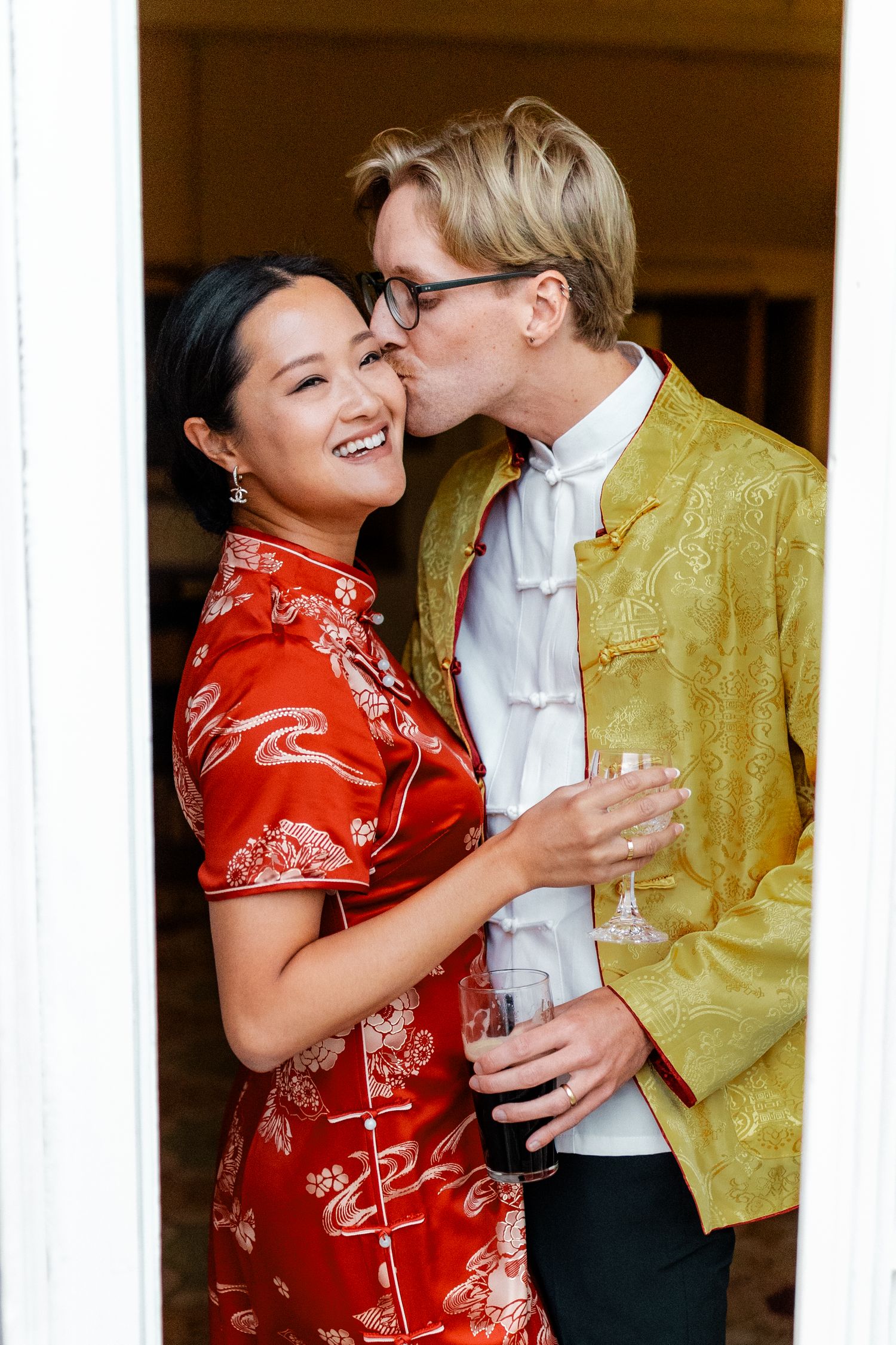Happy couple laughing together during a celebration, one in red qipao dress.