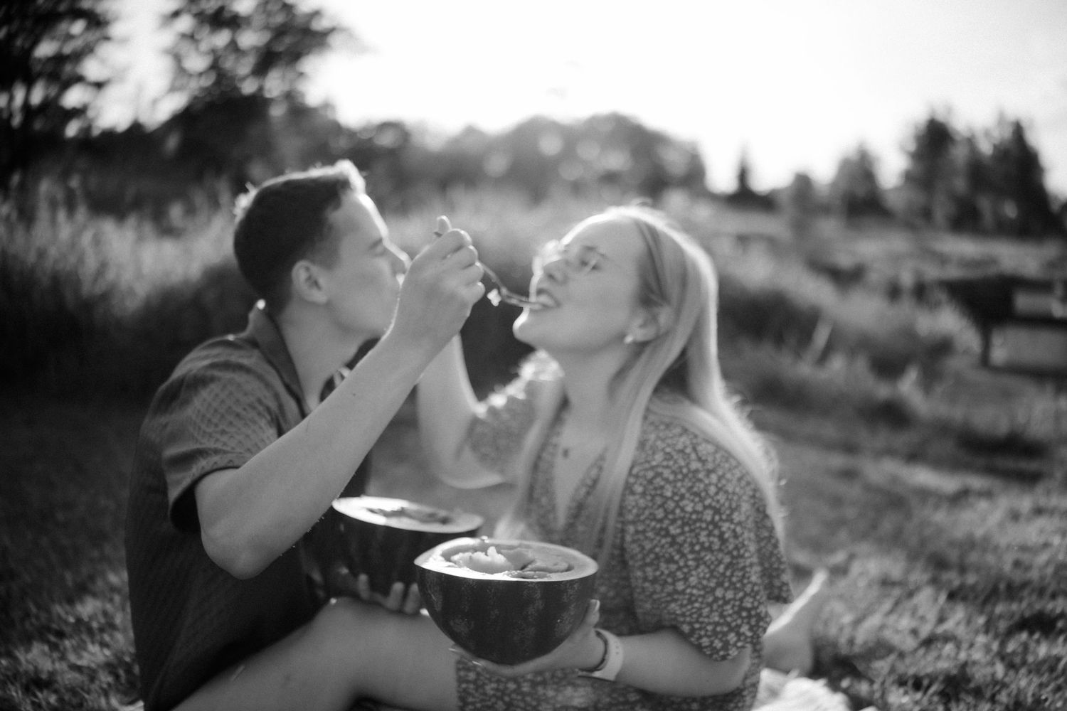 A couple shares an intimate moment in a sunlit outdoor setting.