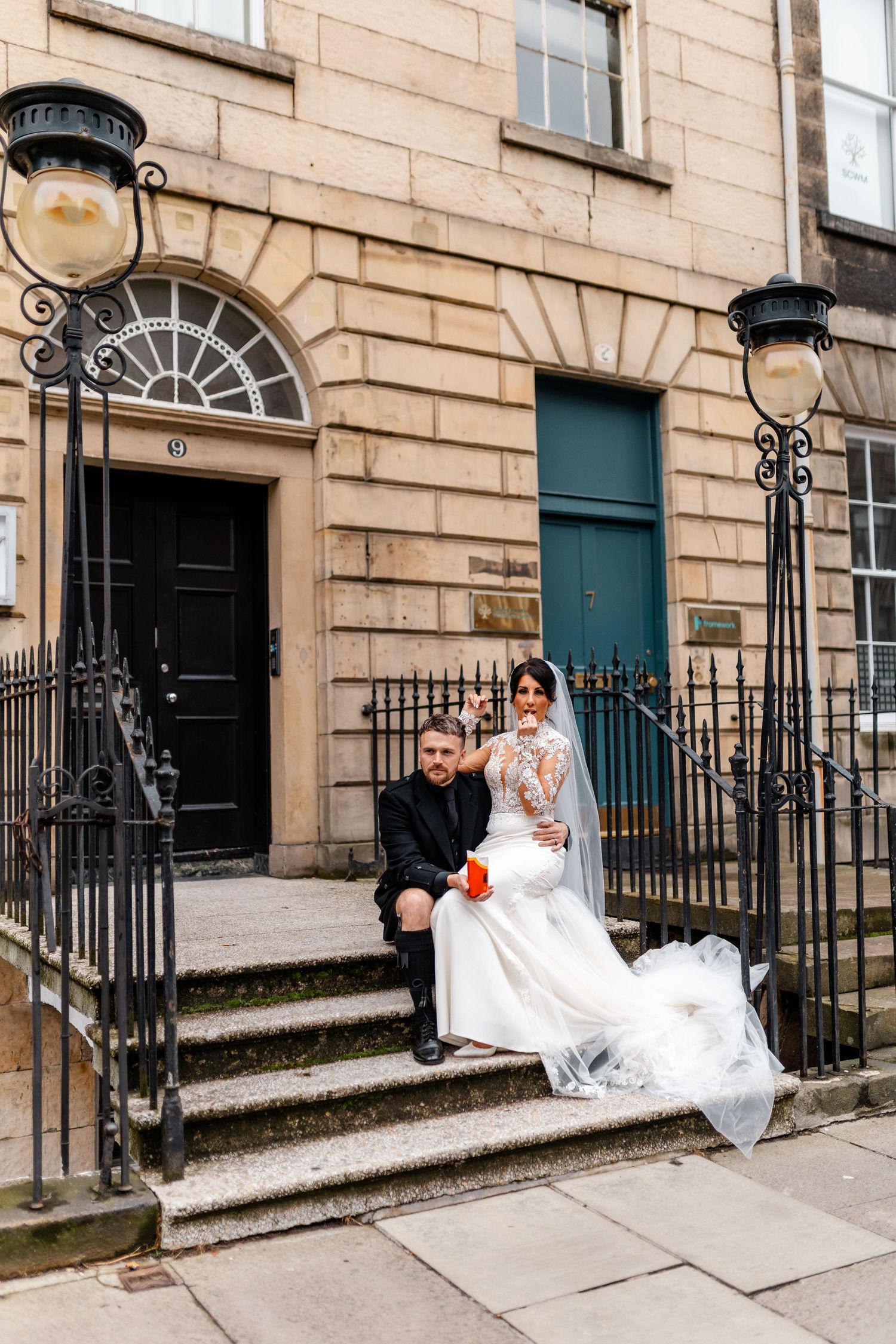 Wedding couple sitting on stone steps of traditional Edinburgh townhouse.