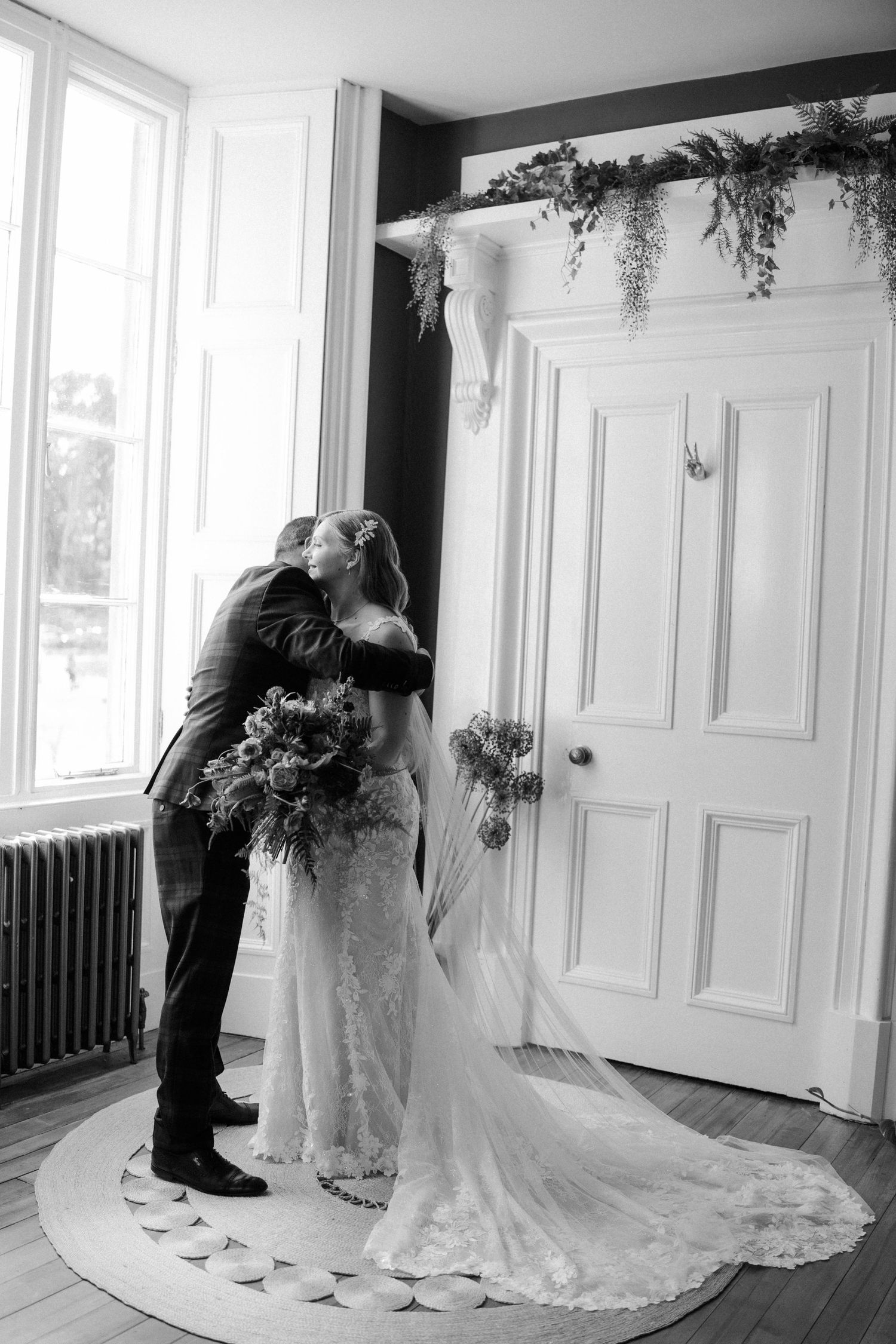 Wedding couple sharing tender moments in an elegant white interior room with ornate moldings.