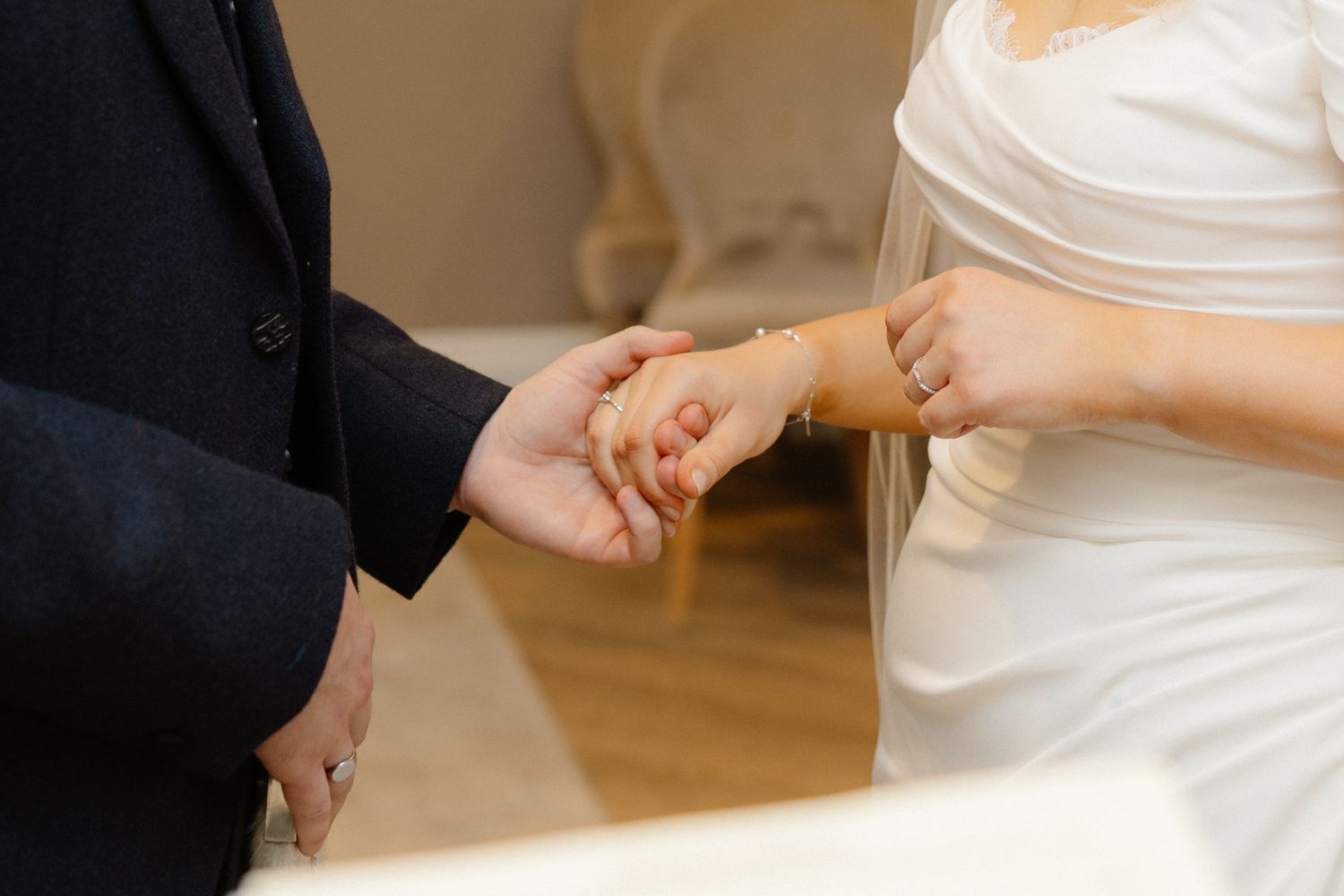 Bride and groom exchanging rings during wedding ceremony, close-up of hands holding together.