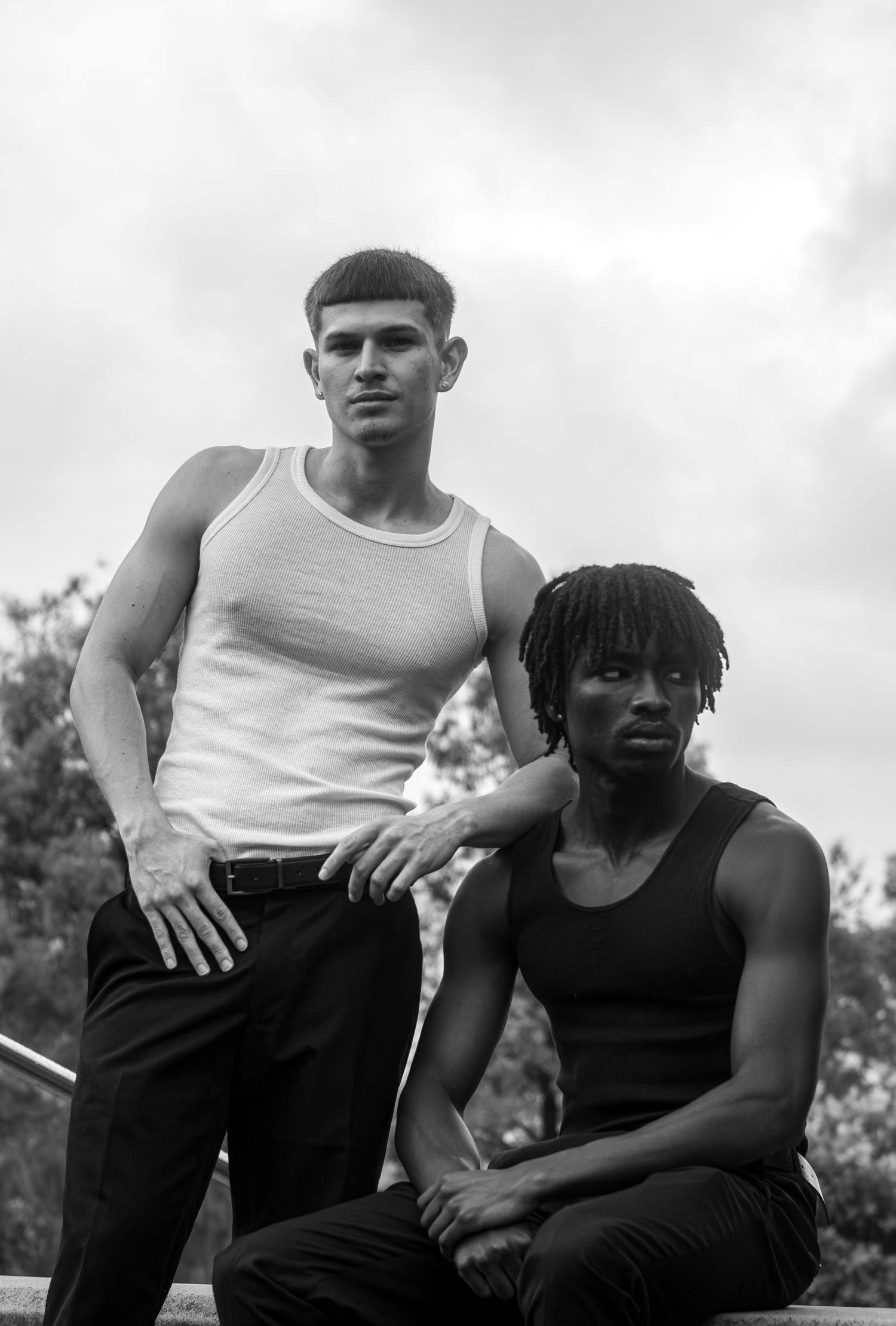 Black and white portrait of two young men posing outdoors together.