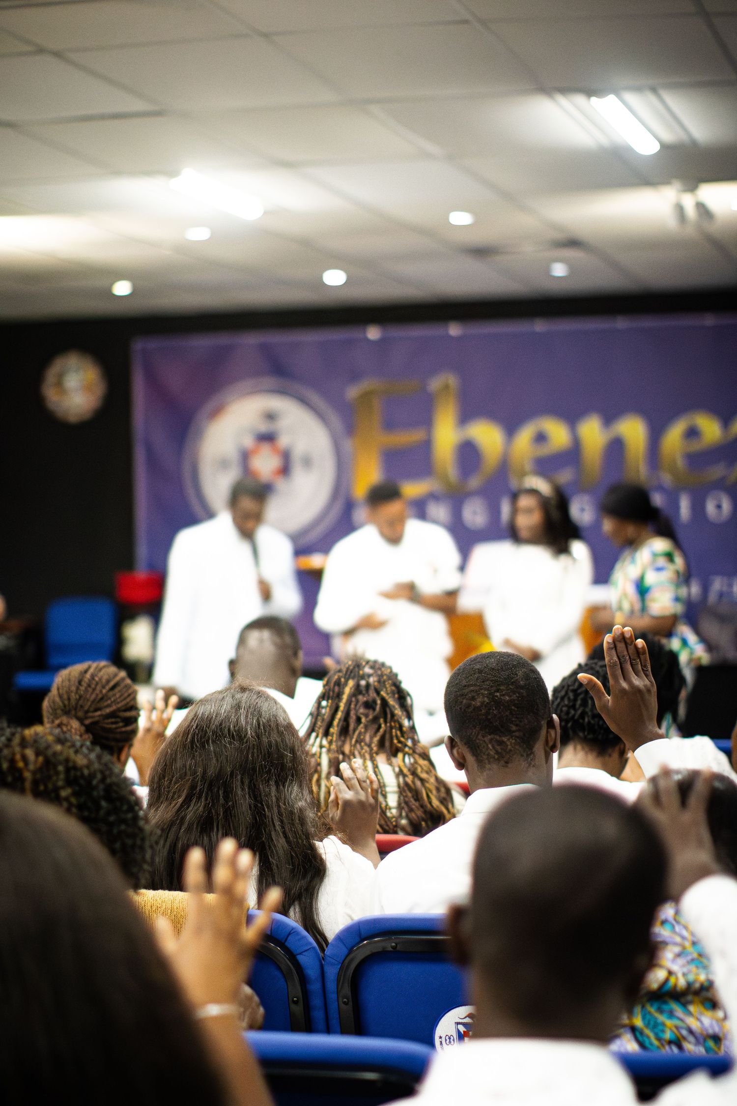 Congregation raises hands in worship at Ebenezer church service.