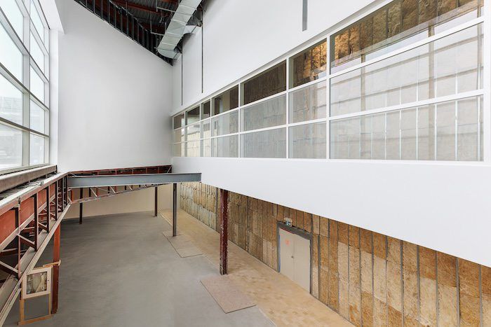 Industrial loft space with high ceilings, clerestory windows, reclaimed wood walls, and concrete floors.