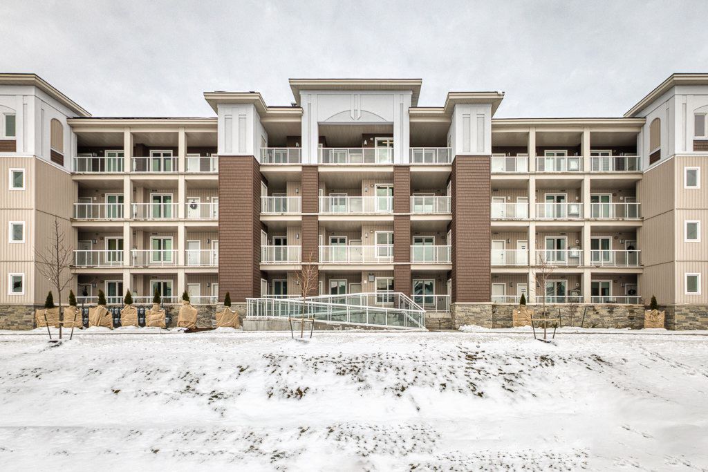 Four-story brick and siding condominium building with balconies surrounded by snow in winter.