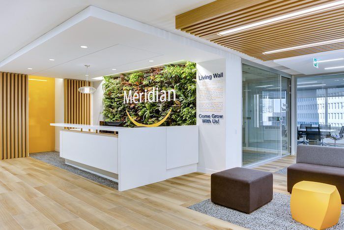 Meridian office reception desk with a lush green living wall, wood accents, and colorful seating area.