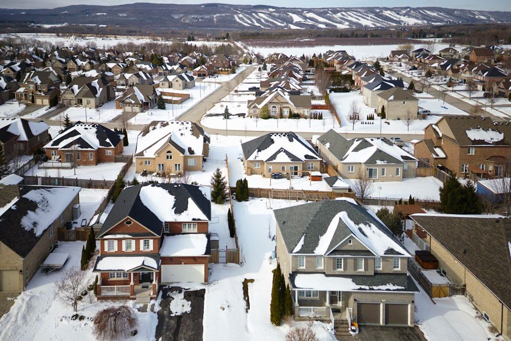 Aerial winter view of a snow-covered suburban neighborhood with rows of residential homes.