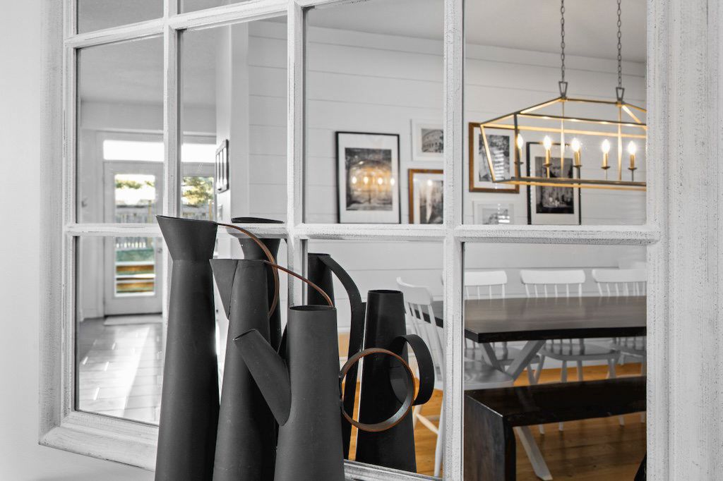 Elegant interior window display with black decorative vases and gold chandelier reflection.
