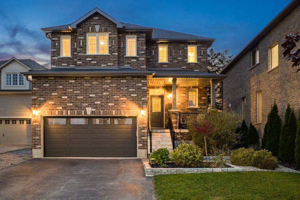 Elegant two-story brick home with double garage and warm exterior lighting at twilight.