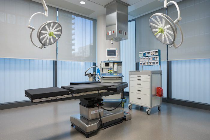 Sterile hospital operating room with surgical lights, adjustable table, and medical equipment on blue walls.