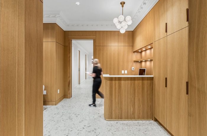 Elegant wood-paneled reception area with terrazzo floors, built-in cabinetry, and a globe pendant chandelier.