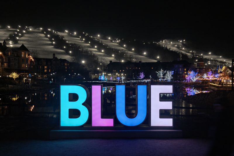 Illuminated BLUE sign at a ski resort at night with lit slopes in the background in Collingwood Ontario