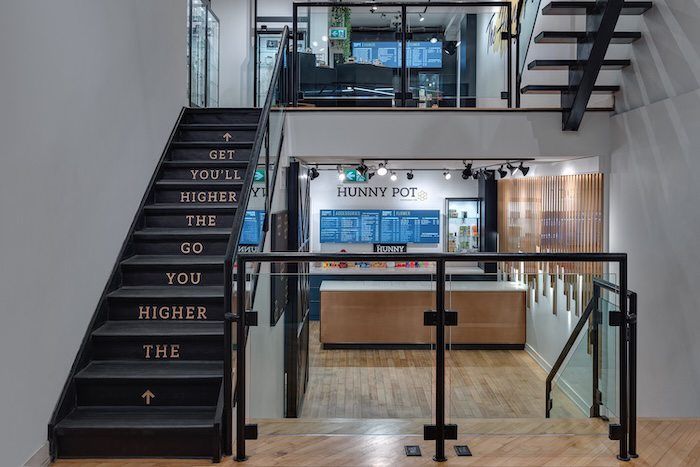 Modern office staircase with motivational text on steps leading to Funny Pot restaurant reception area.