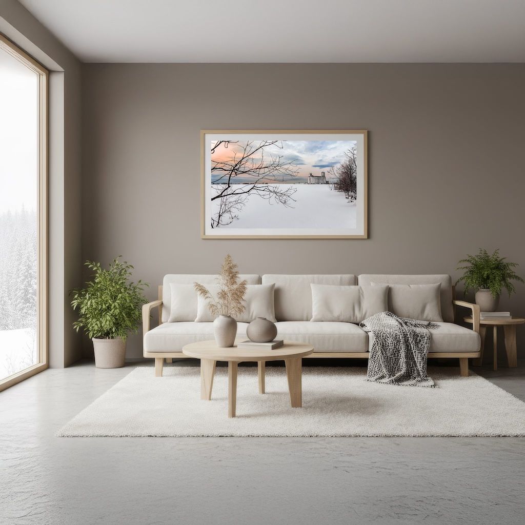 Minimalist Scandinavian living room with beige sofa and winter landscape artwork on taupe wall.